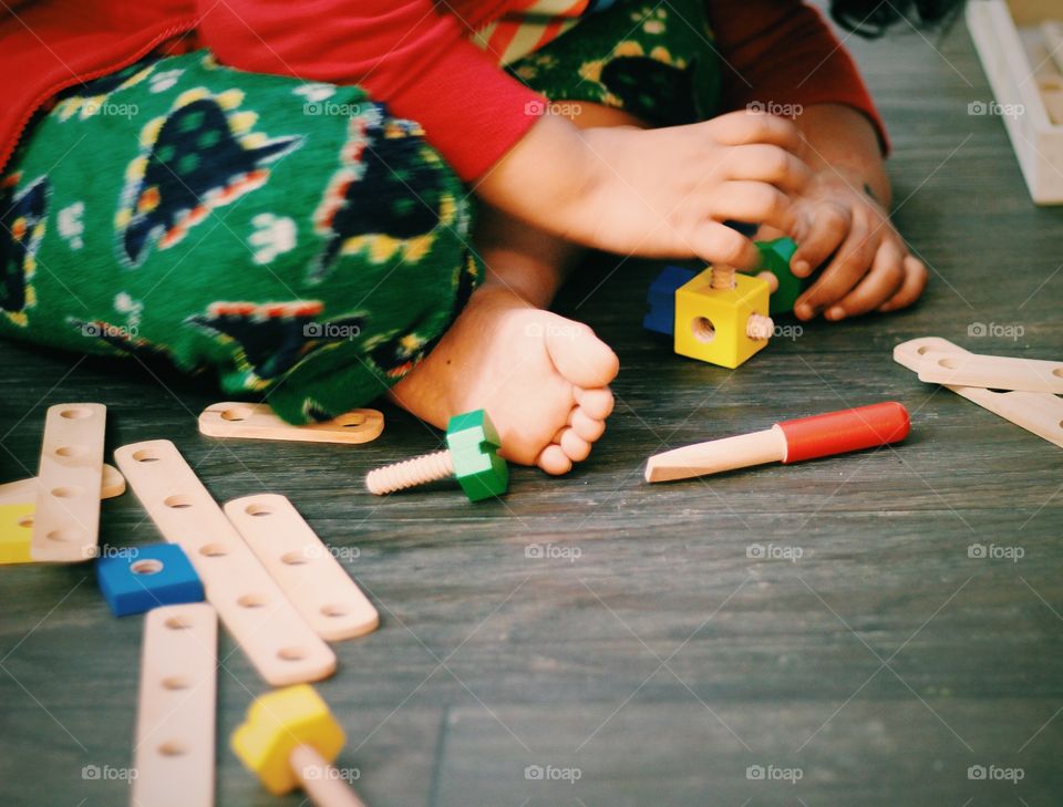 Kid learning use of screws and bolts practically using wooden samples and trying to make creative structures using the same. Learning and fun both at same time