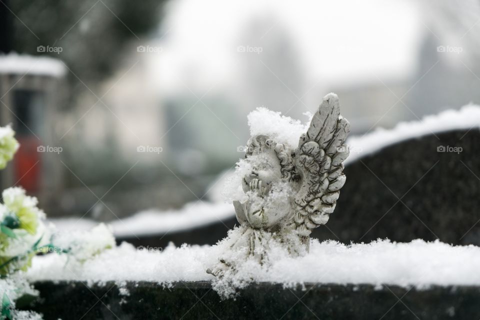 angel statue on cemetery covered by snow
