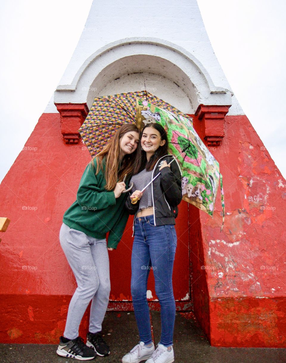 Young women posing at old red lighthouse 