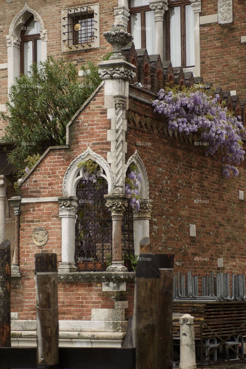 A beautiful view of the city walls decorated with green plants and flowers.  Italy May 2023.