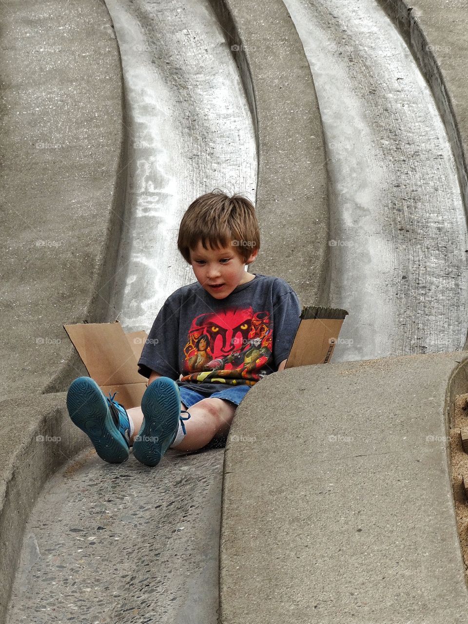 Boy On Slide. Young Boy Riding A Fast Slide At A Playground
