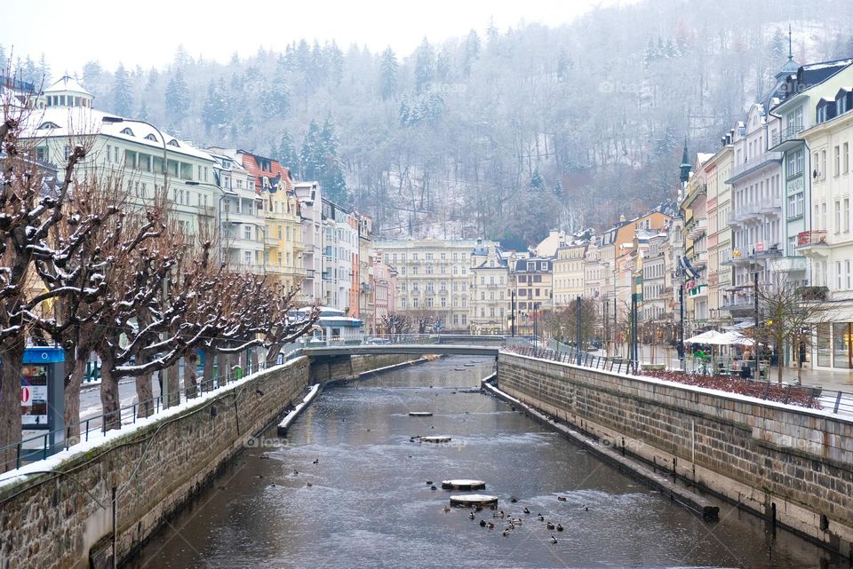A winter view from the bridge to  non-freezing river Tepla and snowy Karlovy Vary city