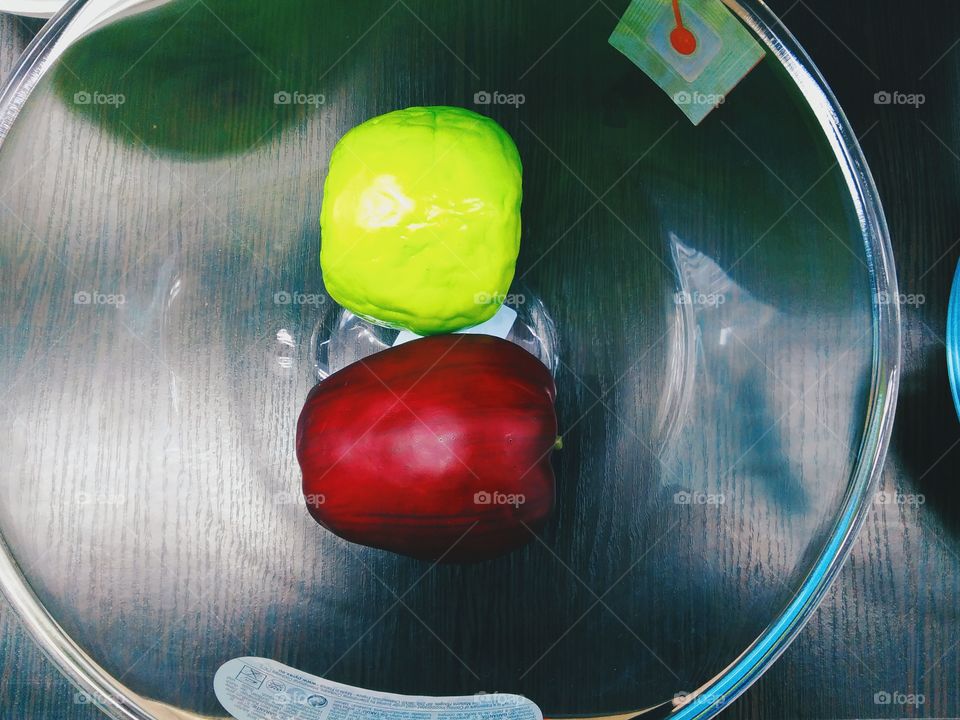 red and green apples lie in a glass bowl