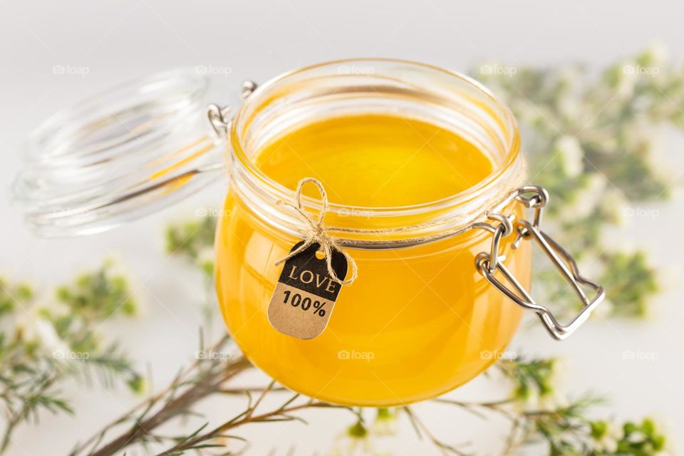 Organic honey in glass jar on a light neutral background with flowers. Honey is a natural, folk medicine. Immune boosting food. Soft image and soft focus style