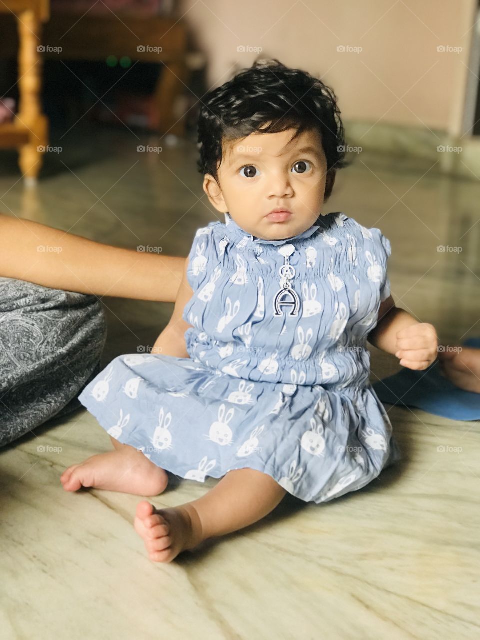 Cute Indian baby girl sits on the floor 