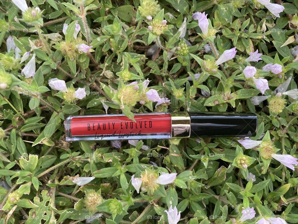 Red lip gloss in purple flowers