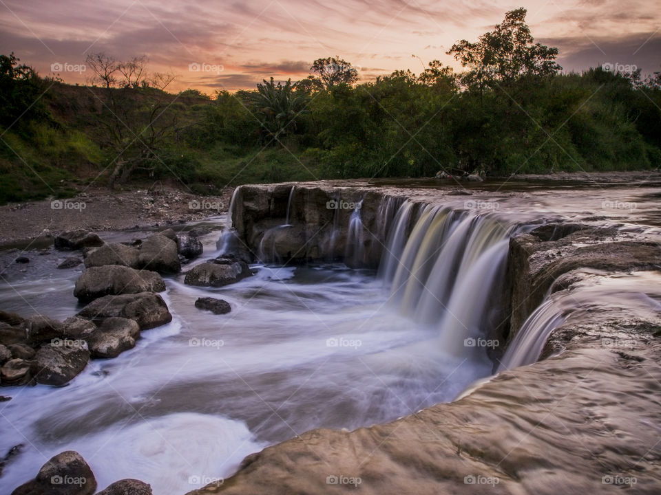 Scenic view of waterfall at sunset