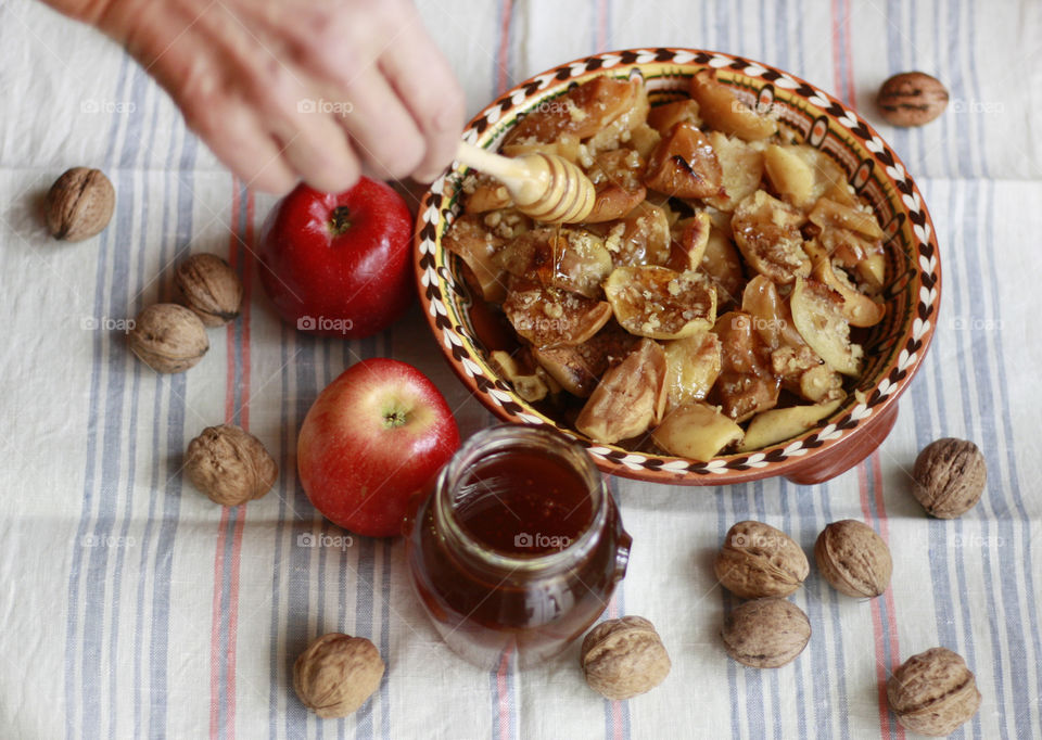 Baked apples with honey and walnuts on the rustic table