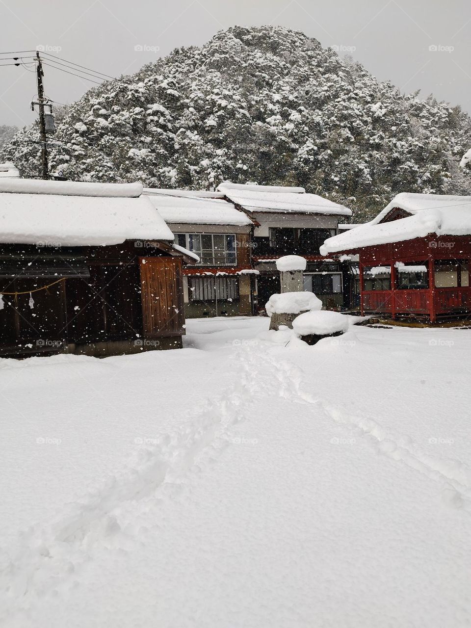 A peaceful snowy village nestled at the foot of a mountain, capturing the quiet beauty of winter.