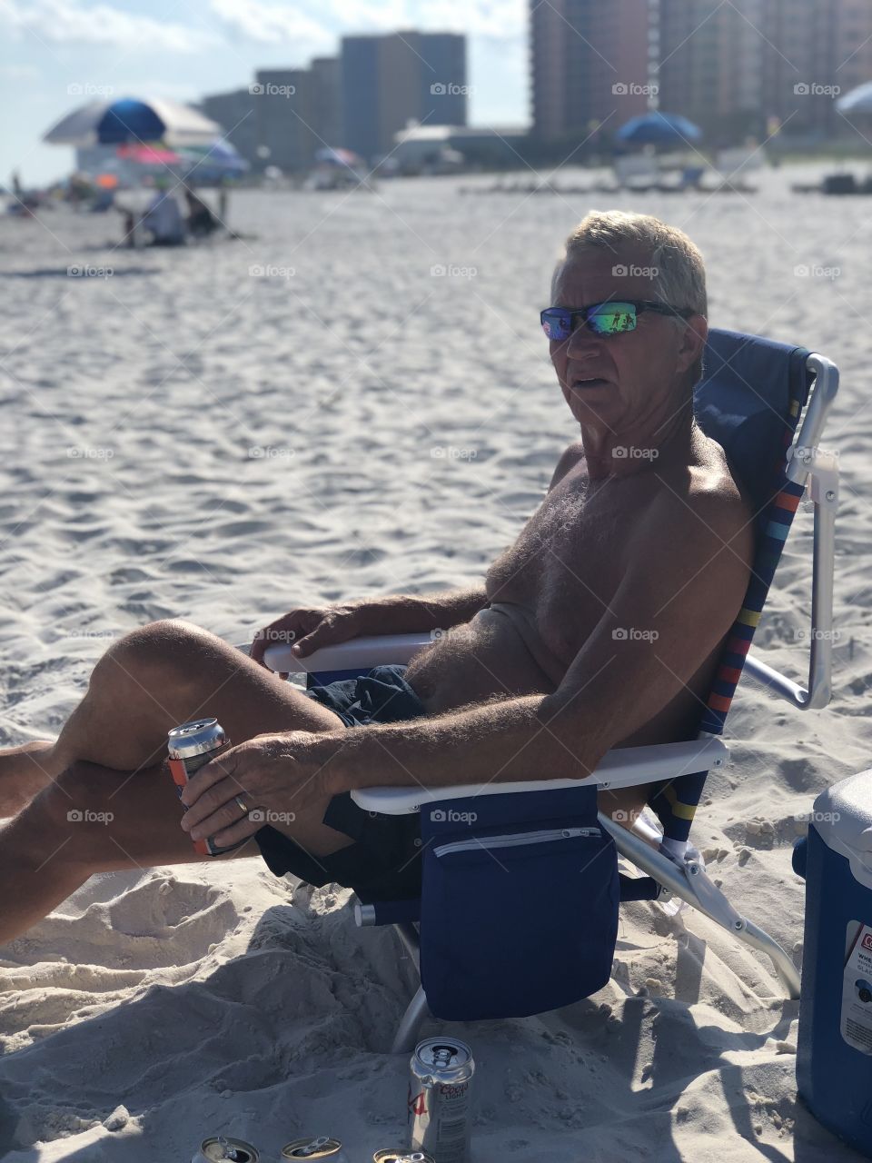 Male enjoys drinking beer on orange beach in Alabama’s Saturday night life.