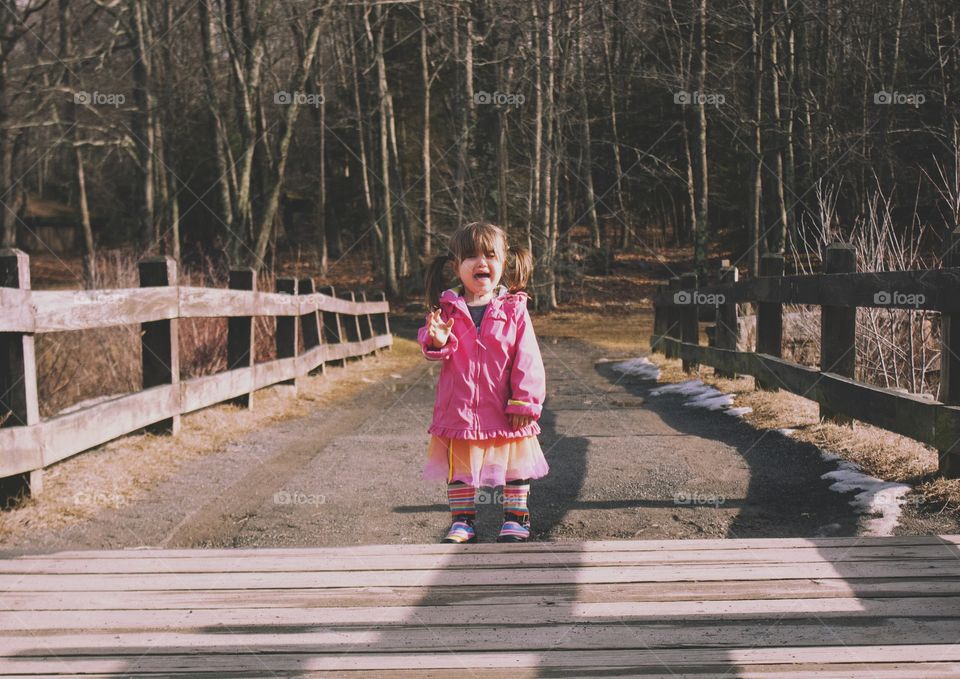 Girl standing on footbridge crying