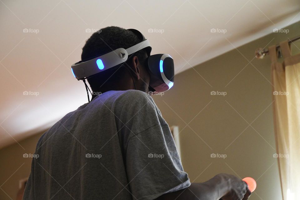 A young man engages in a session of virtual reality gaming in the living room of his home.