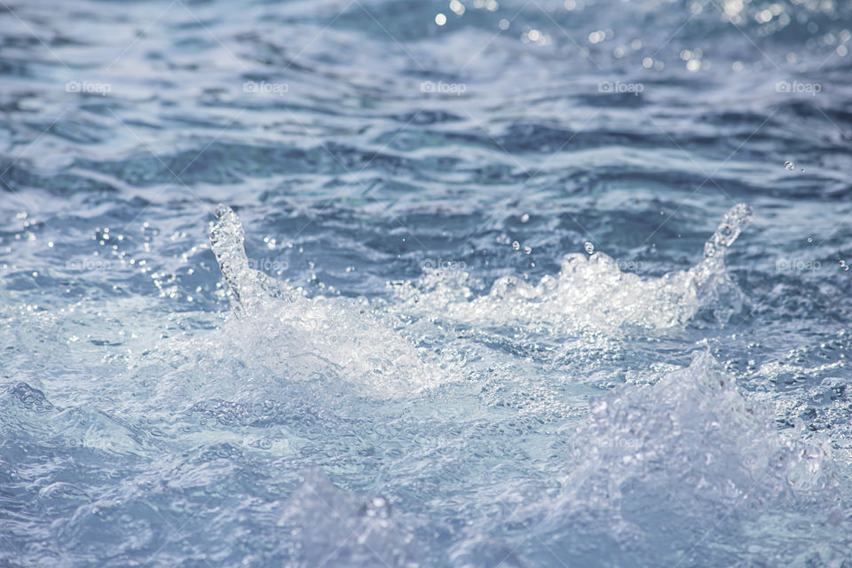 The blue water waves by wind and sunlight reflecting surface