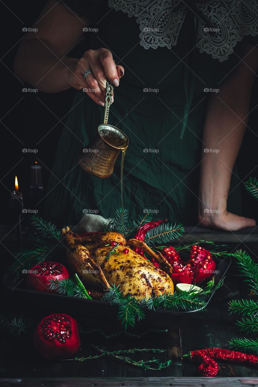 Golden turkey served to the table with pomegranates and decorated with coniferous branches is a festive dinner, a restaurant dish. The pinnacle of the chef's skill. Home sweet home. Family holiday traditions.