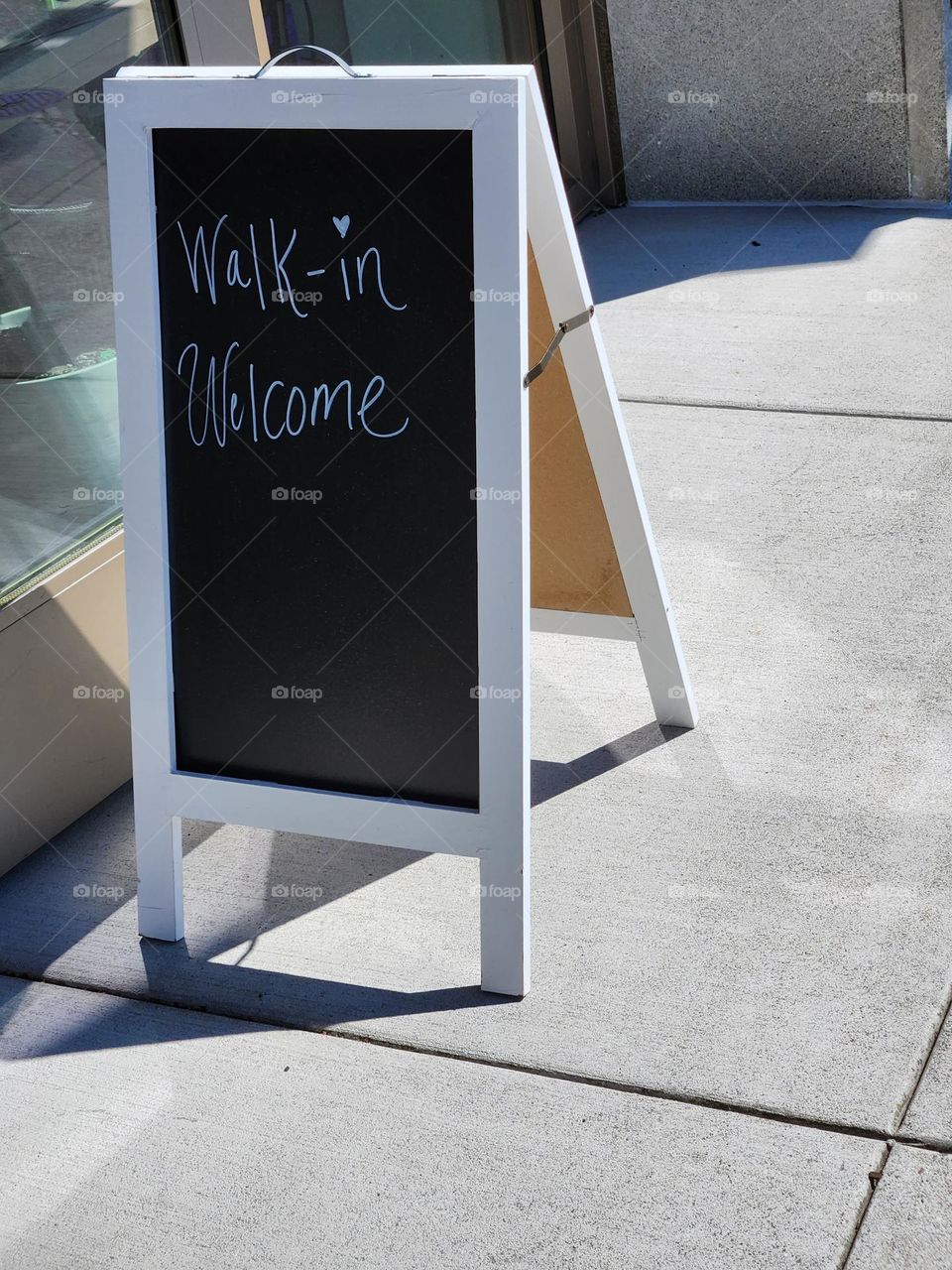 black and white walk-in welcome chalk sidewalk sign in front of salon