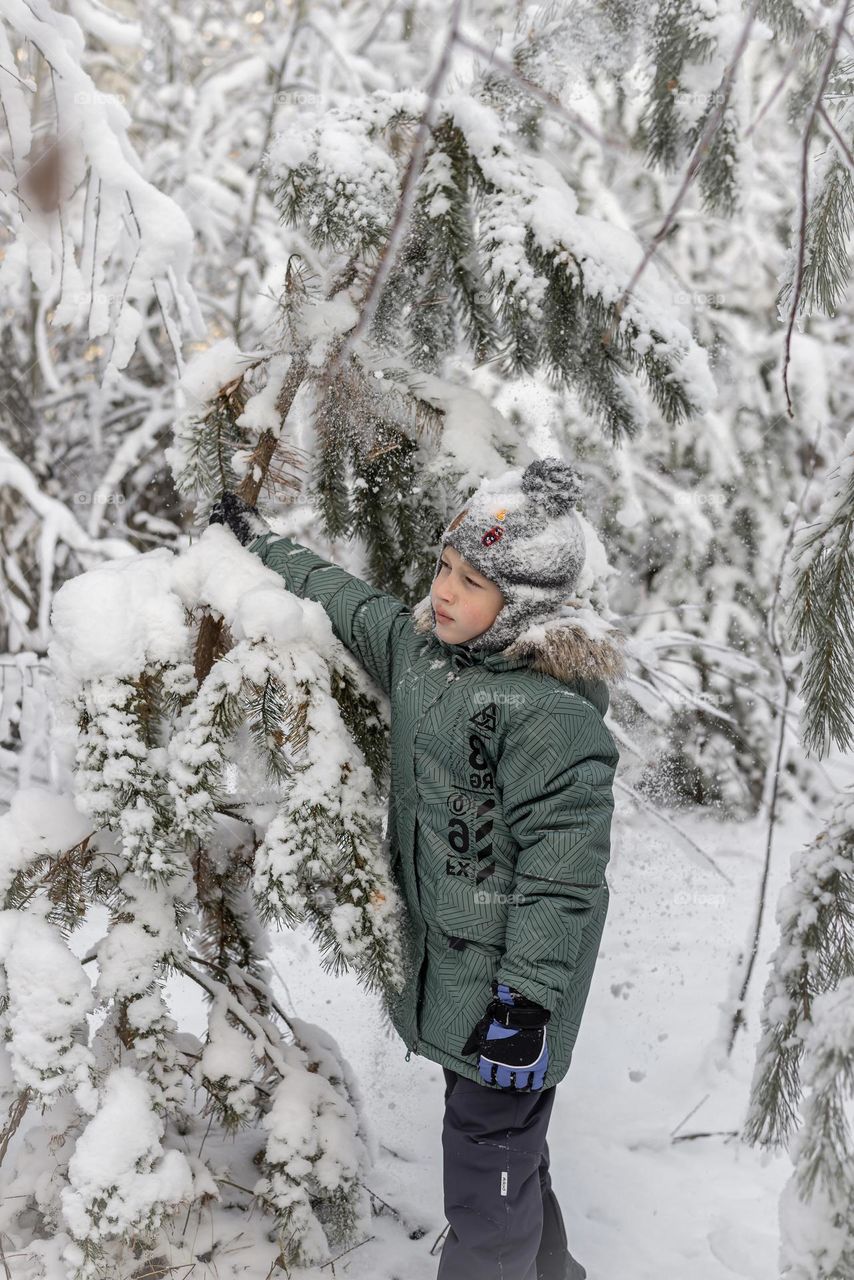 Child in green clothes in winter forest 