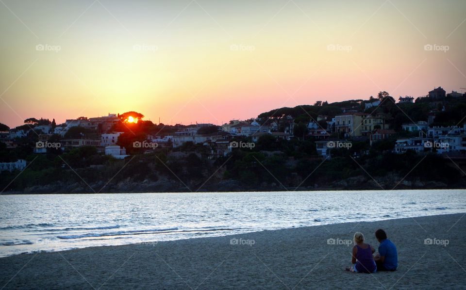 Couple relaxing on beach at sunset