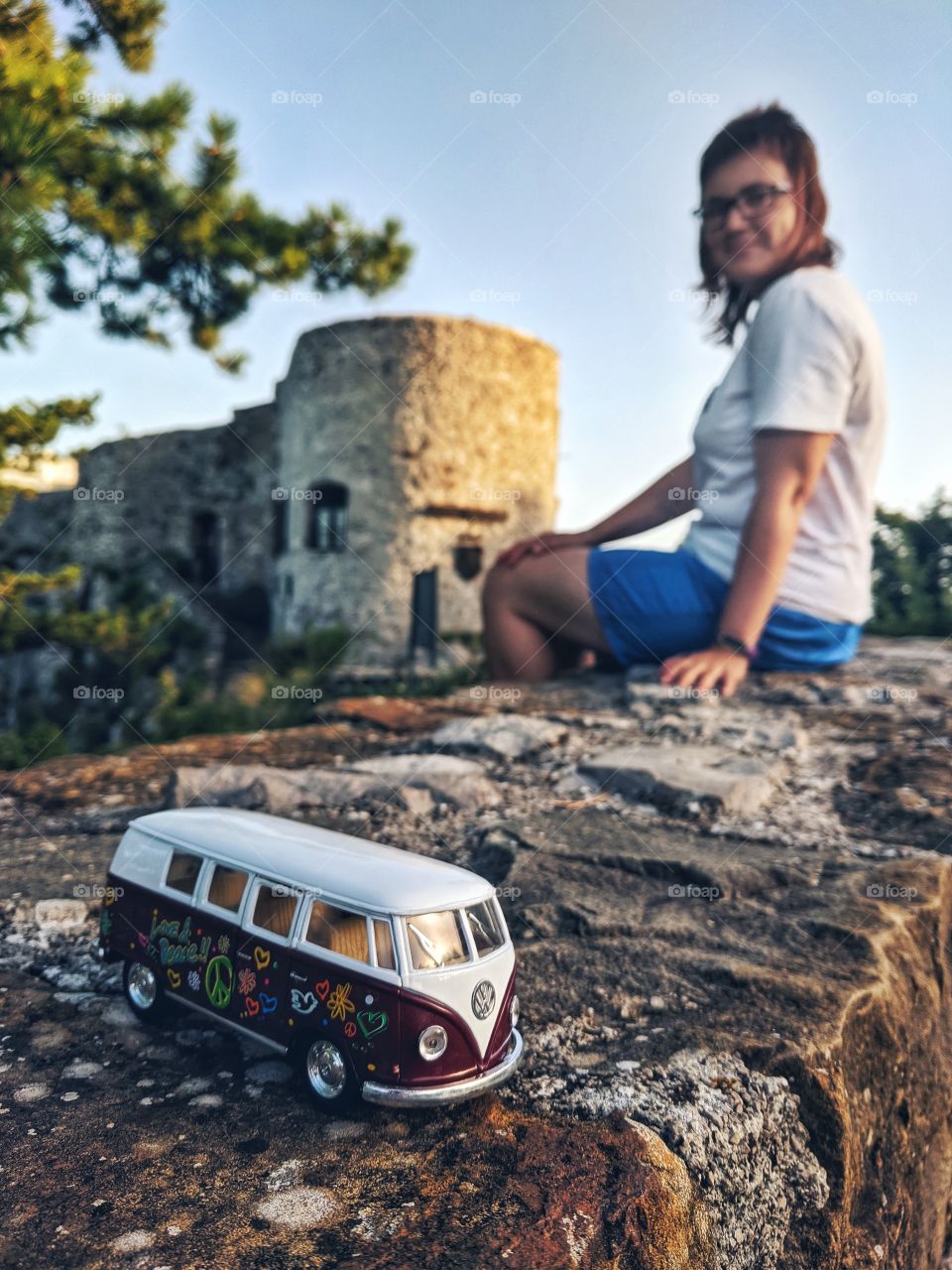 Young happy woman with tiny bus- toy like a symbol of road adventures. Traveling concept.