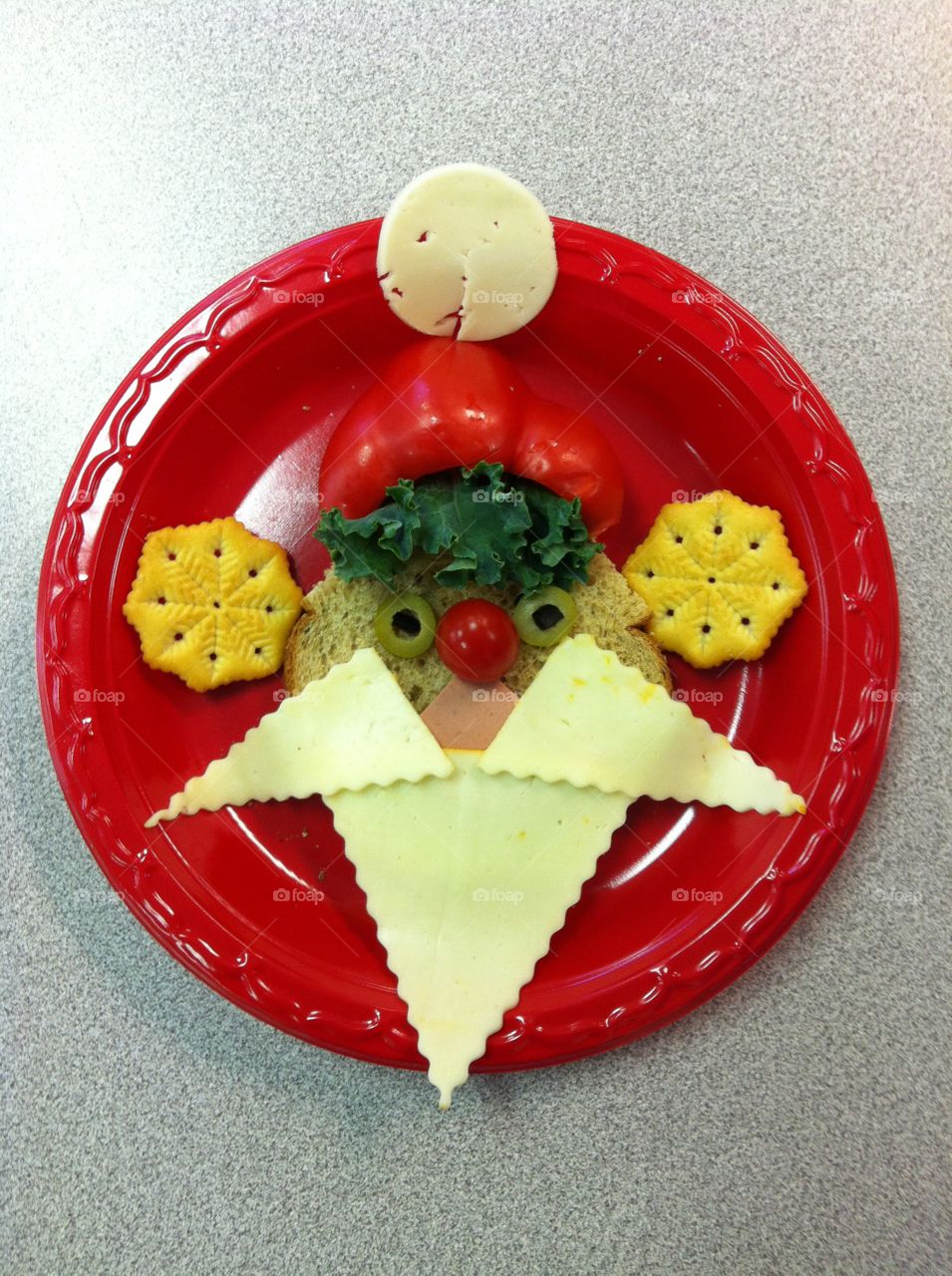 Santa Clause sandwich on a red plate. Bread, cheese, red bell pepper, crackers, green olives, cherry tomato, lettuce leaves. Healthy and yummy.