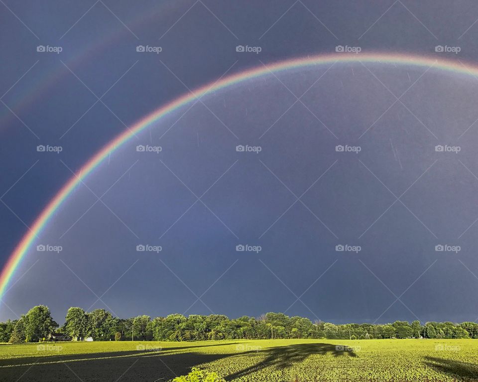 After a long rain from dark skies, a rainbow comes to grace the early-summer sky. A dazzling show of mezmorizing color and dramatic shadows.