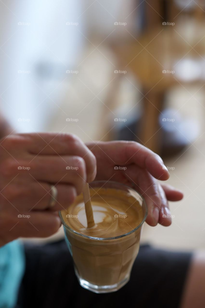 Hands from a man stirring coffee