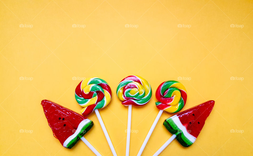colorful round Lollipop and Lollipop in the shape of a watermelon, handmade in the evening in autumn on yellow background