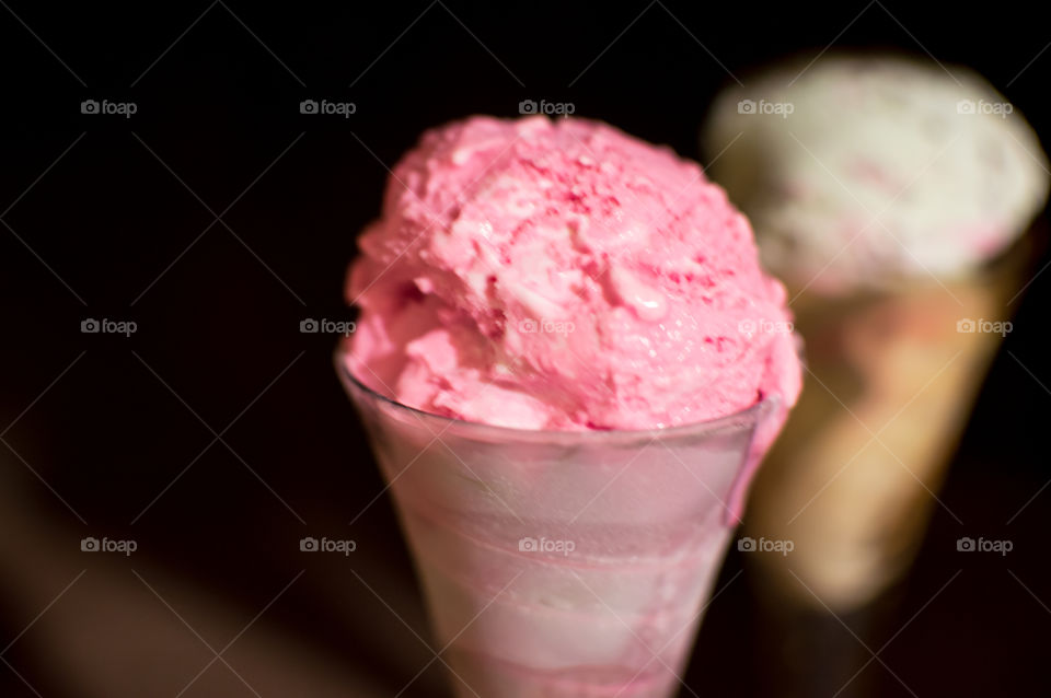 Closeup of pink ice cream in cone shaped crystal glass on wood background 