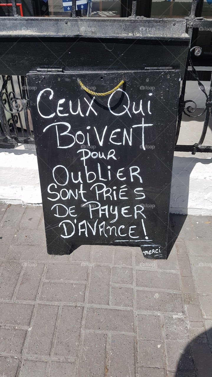 Unusual warning in a front of a bar that can be translated by 'those who drink to forget are asked to pay in advance. Thanks'. Montréal, Québec, Canada.