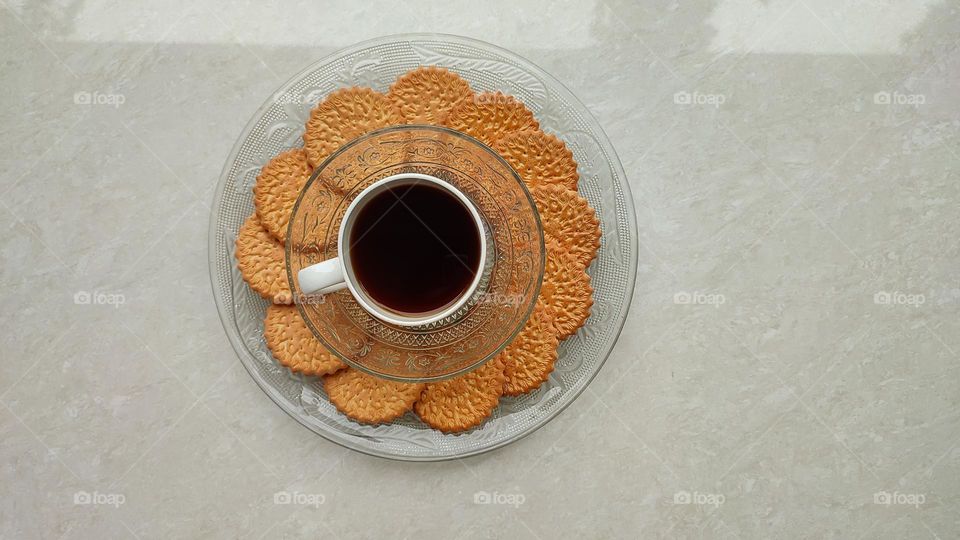 Coffee with biscuits, coffe in a white ceramic glass and biscuits in a transparent glass plate