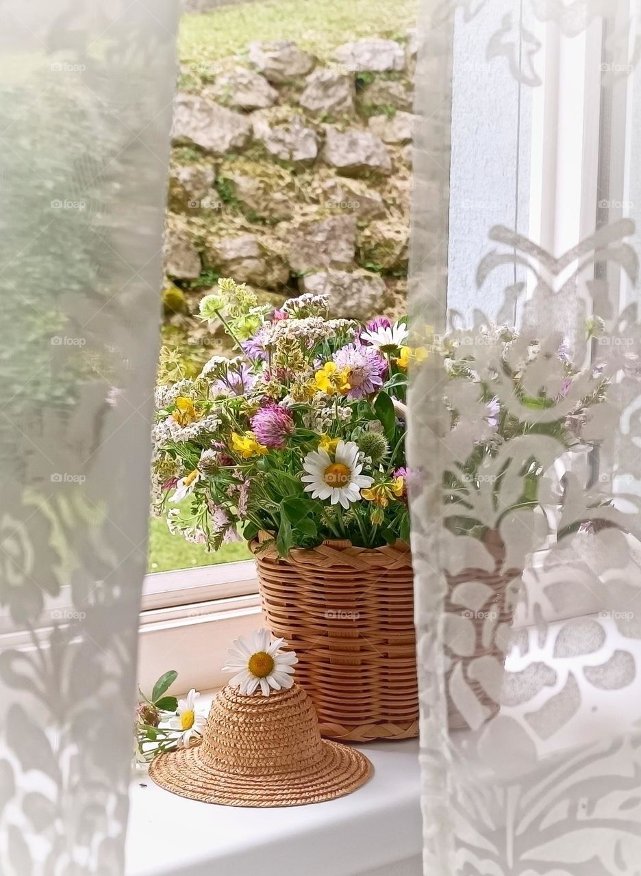 Bouquet of wild flowers in a wicker basket on the window