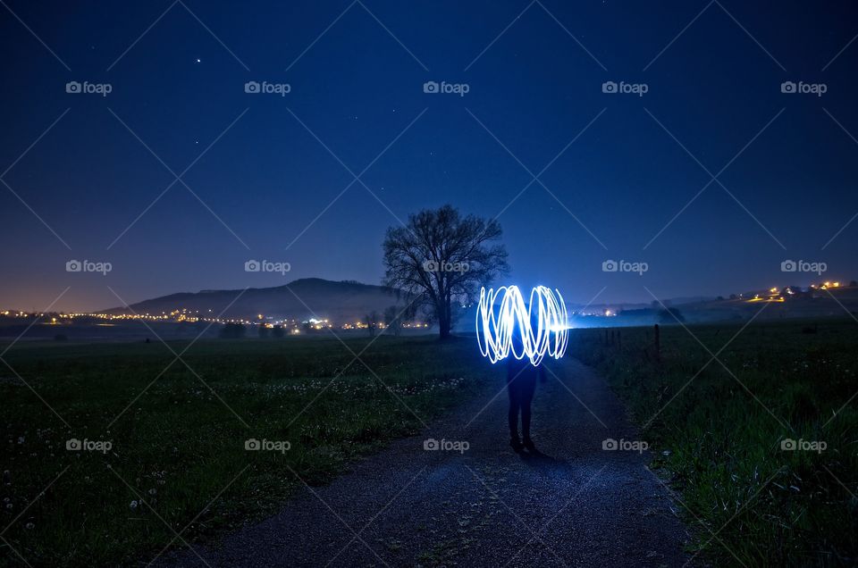 One person light painting outdoors at night 