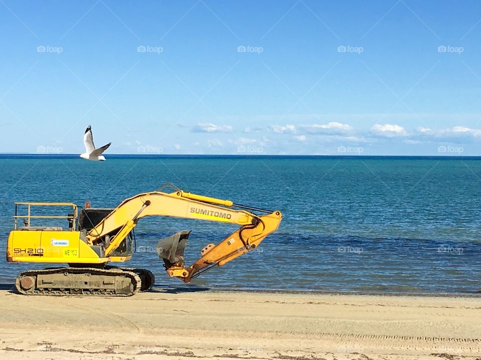 Heavy machinery yellow excavator on south Australian beach 