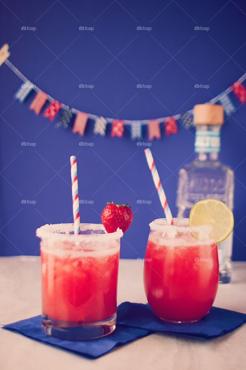 Altos Tequila and Margaritas. Two strawberry margaritas in a festive Independence Day setting, with tequila bottle in the background.