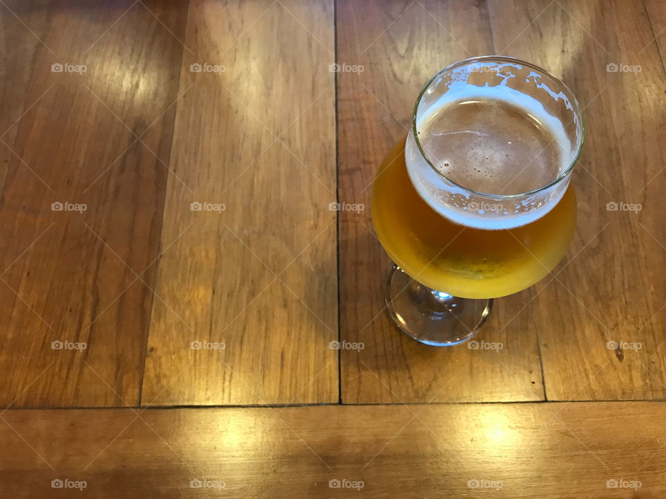 glass of fresh cold draught beer with smooth white beer foam is putted on wood table with its nice shadow and natural lighting with copy space on left side of frame, for refreshing after the tired day