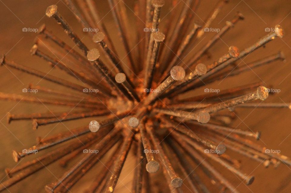 An art piece of metal rustic nails in the shape of a spherical sculpture rest on top of a bedroom dresser.