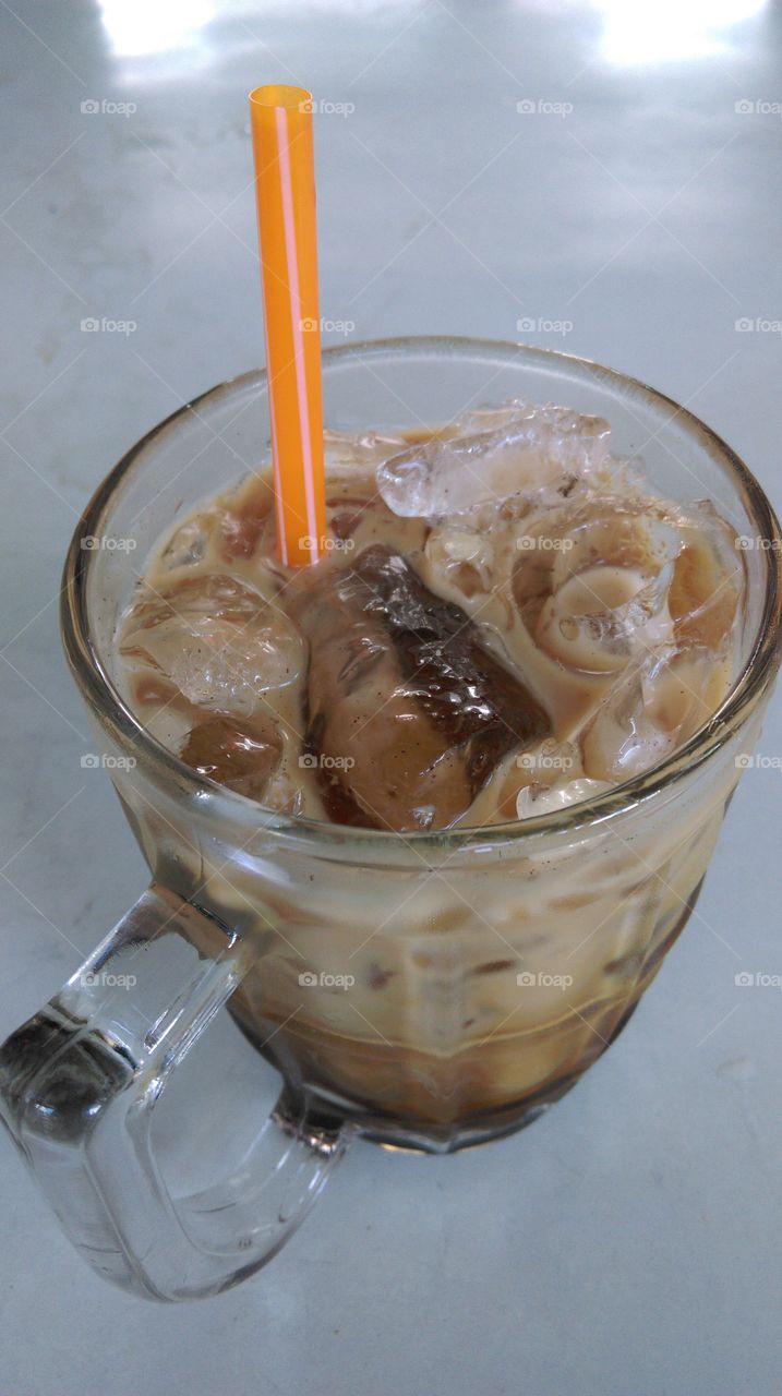 A glass of traditional coffee with ice cube