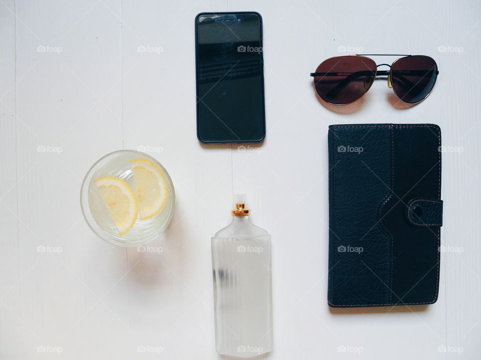 notebook, glasses, smartphone, eau de toilette and lemonade on a white background