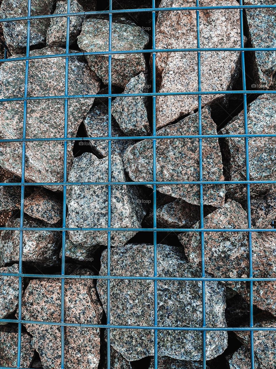 Grey rocks behind a green mesh.