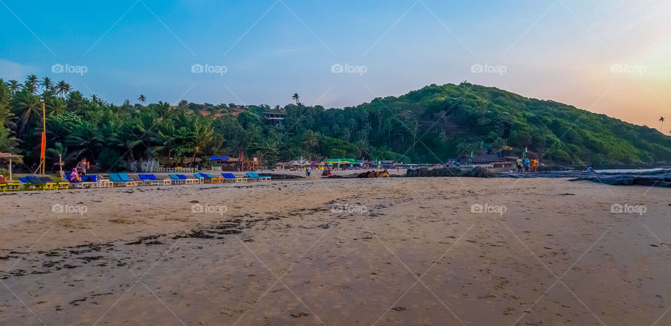 beauty of Beach-It is beach side nature with blue sky and hill propped with green trees on top.