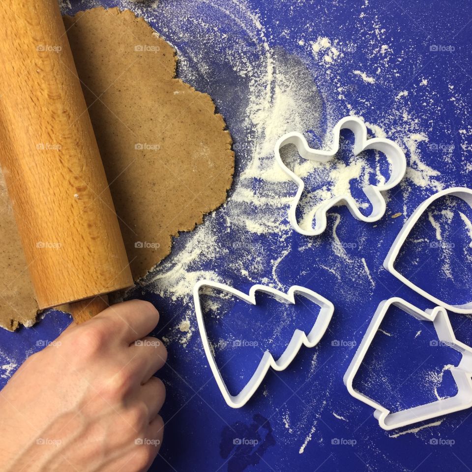 Person rolling dough using rolling pin for cookies