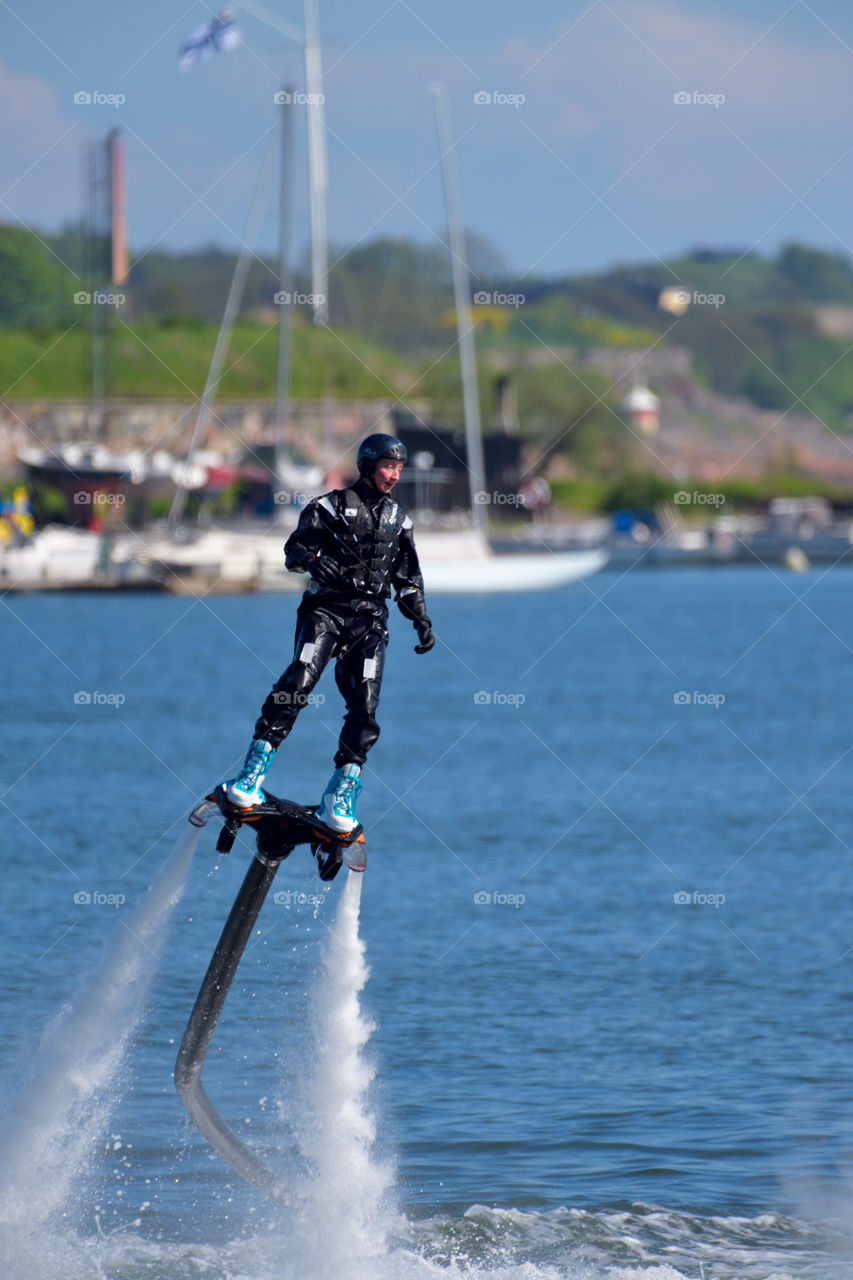 Helsinki, Finland - June 9, 2017: Unknown man performing hydroflight stunts with water jetback at the Kaivopuisto Air Show with Suomenlinna fortress island on the background on sunny summer evening above the Baltic Sea in Helsinki, Finland.