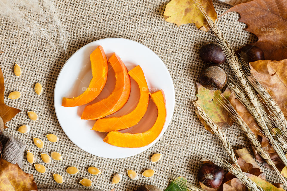 Flatlay with sliced pumpkin, chestnut and fallen leaves 