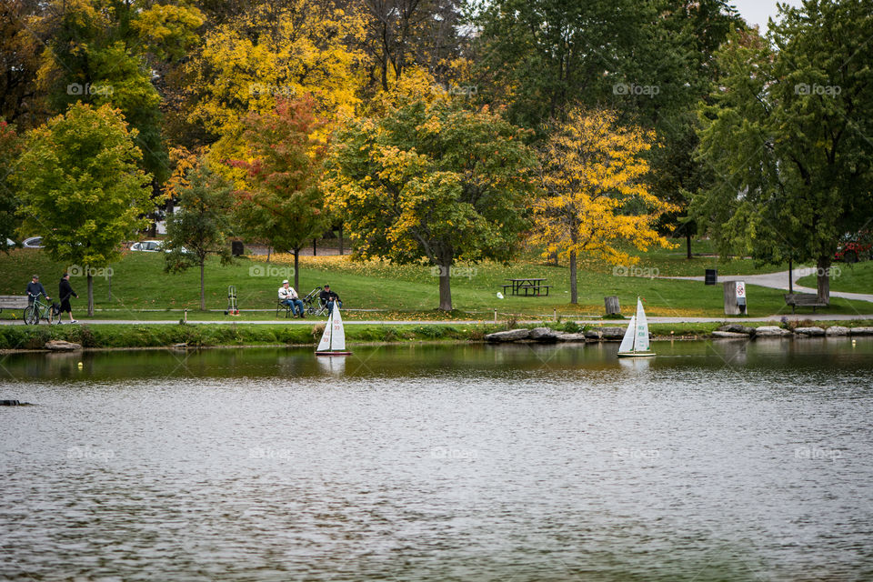 People enjoying a beautiful autumn morning at the pond racing collectable yachts