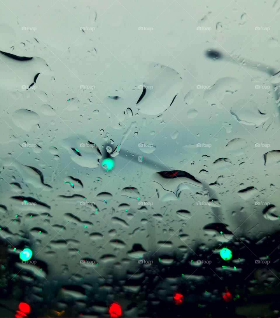 rain drops on the glass of the car and traffic lights