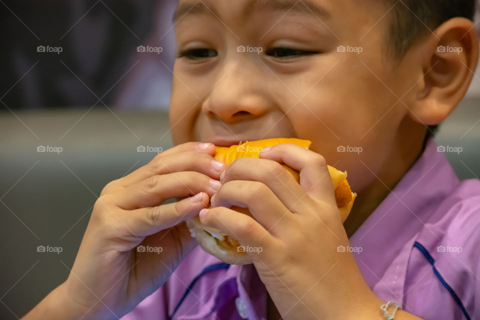 Hamburger fish in hand asia boy holding the eating.