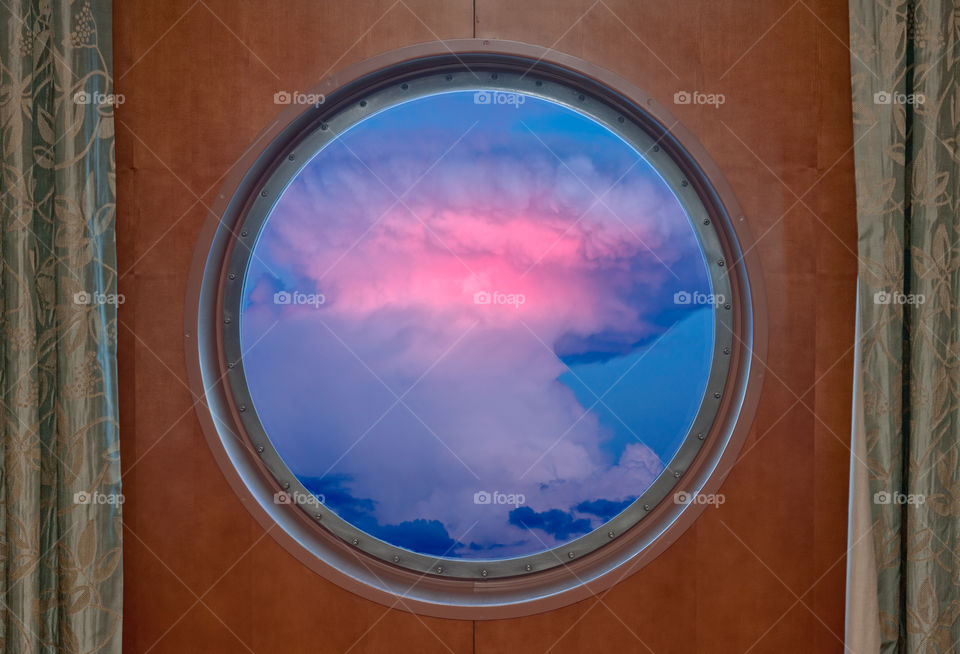 Cumulonimbus thunderstorm cloud seen through the porthole of a cruise ship
