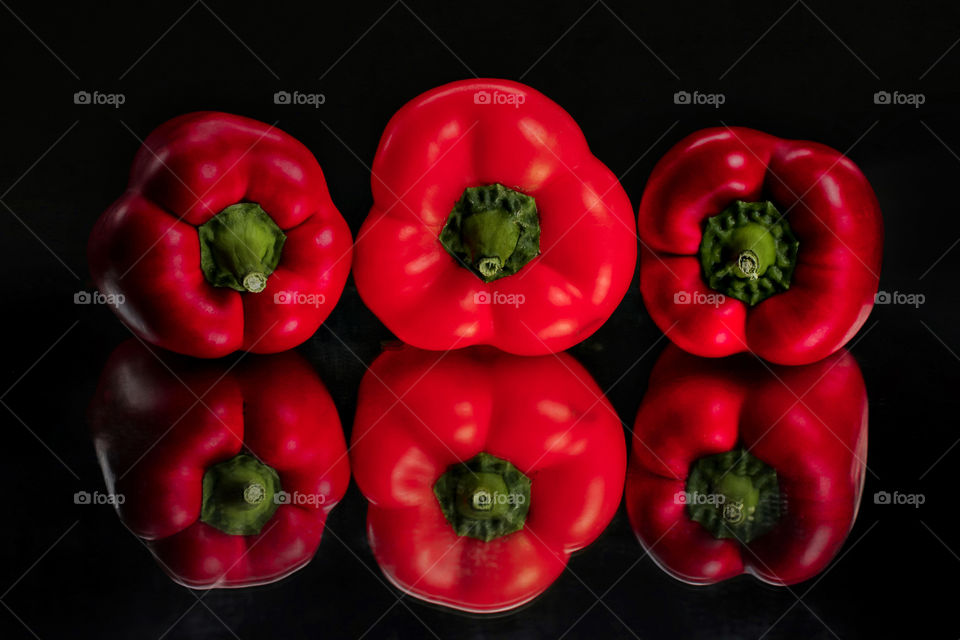 Three red peppers on black background 