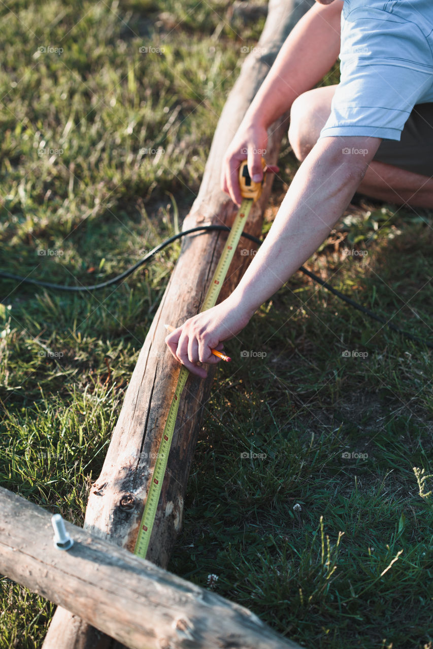 Man using steel tape measure to measuring of timber while working in garden