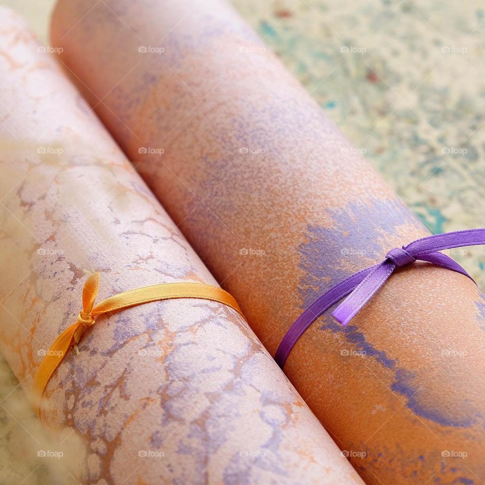 An approximate closeup of a purple tie tightening a fancy paper roll