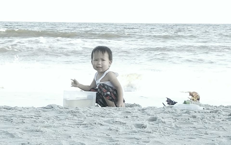 Asian boy playing in sand at sea shore